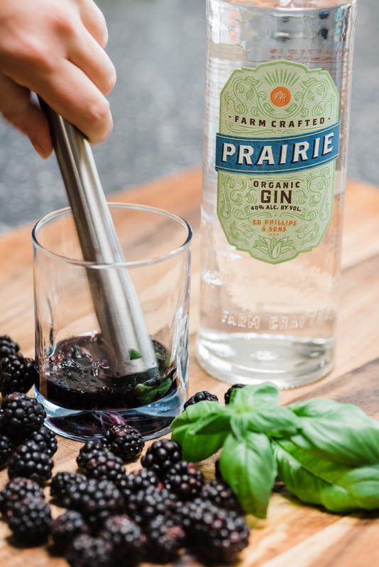 muddling blackberries in a glass for a gin cocktail