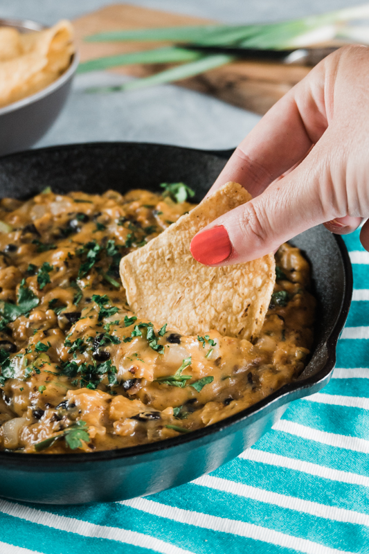 dipping a chip in vegetarian chili cheese dip