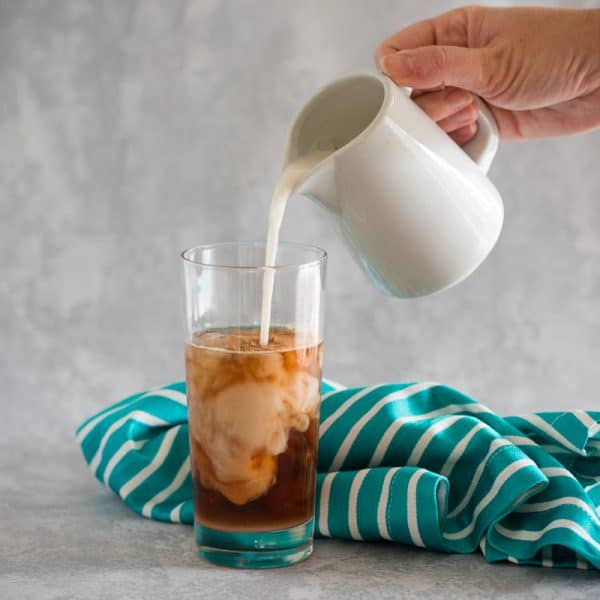 pouring almond milk into vegan thai iced tea