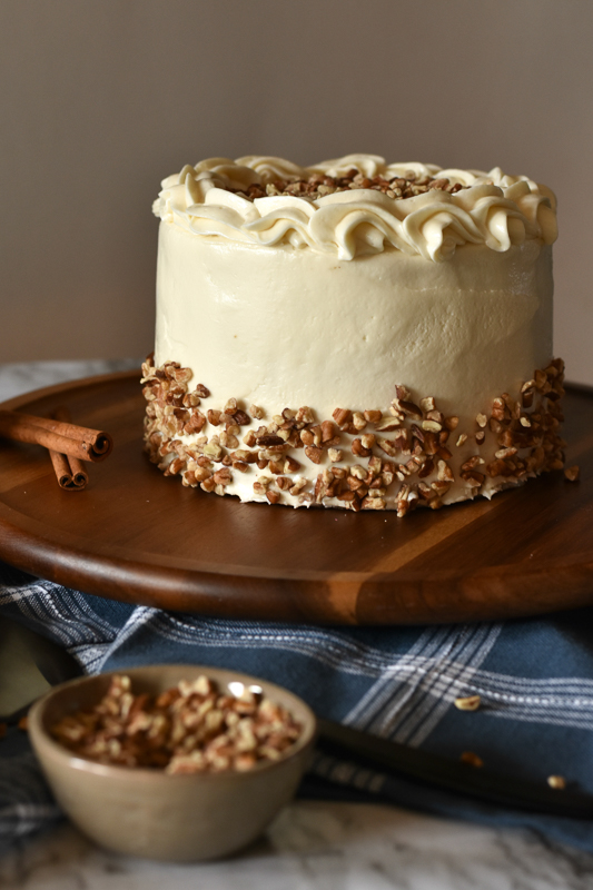 vegan carrot cake with maple cream cheese frosting being served on a table