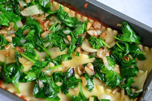 layering spinach filling onto vegan lasagna