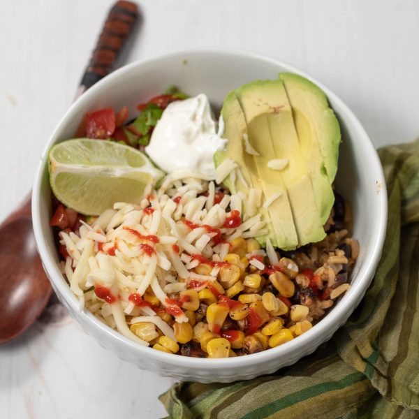 vegetarian burrito bowl topped with avocado, cheese, and sour cream