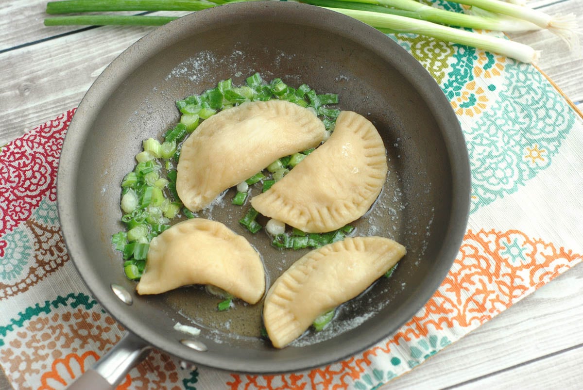 homemade pierogies sautéing with onions in a pan