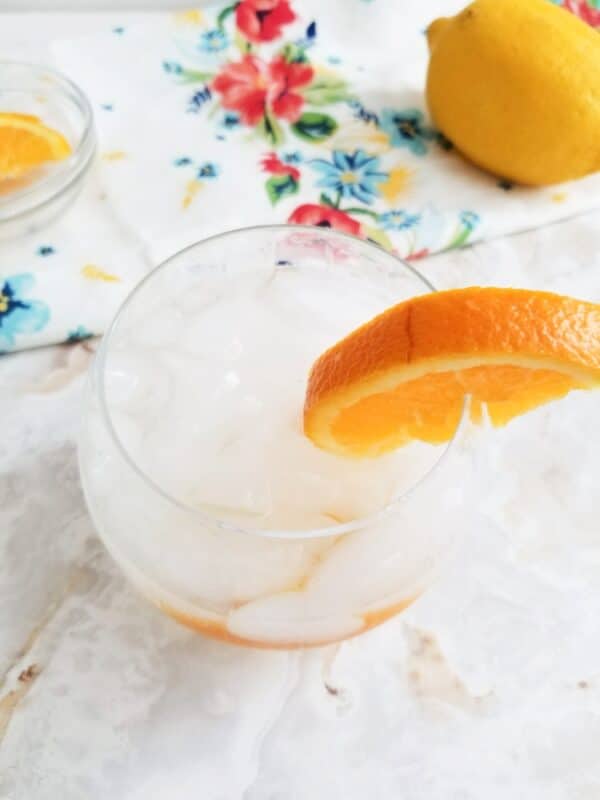 tom collins cocktail being served with a slice of orange and a colorful napkin