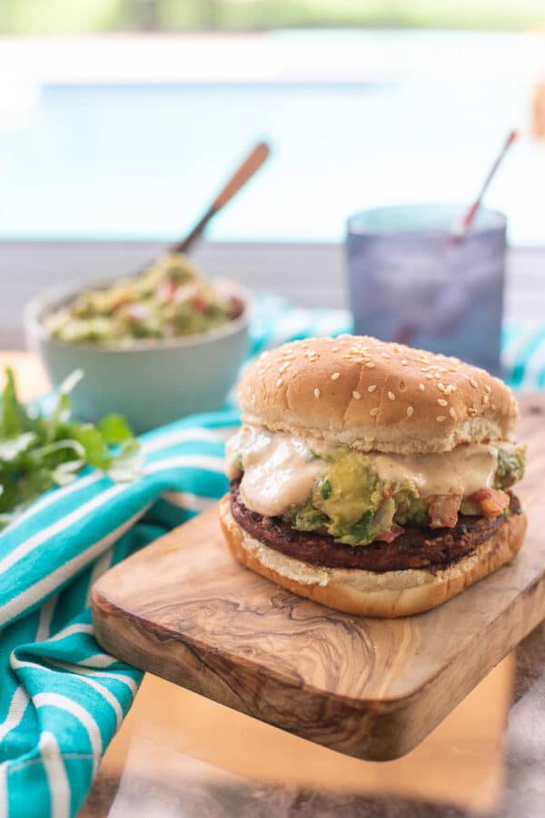 guacamole veggie burger being served on a wooden tray