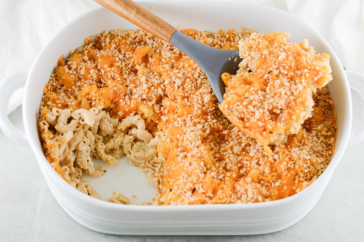 baked vegan mac and cheese in a white dish with a spoon