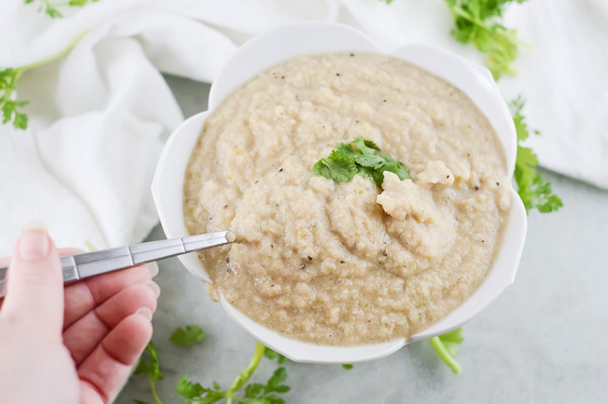 vegan cauliflower soup being scooped in a spoon