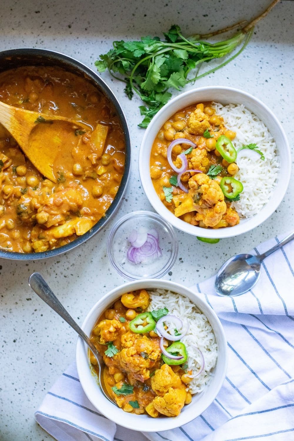 two bowls of vegan chickpea curry next to pot