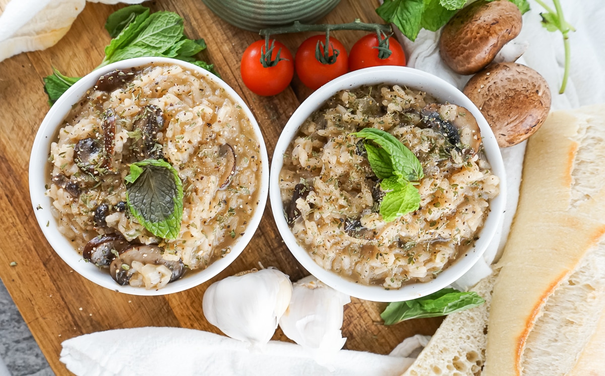 two bowls of vegan mushroom risotto with tomatoes and French bread