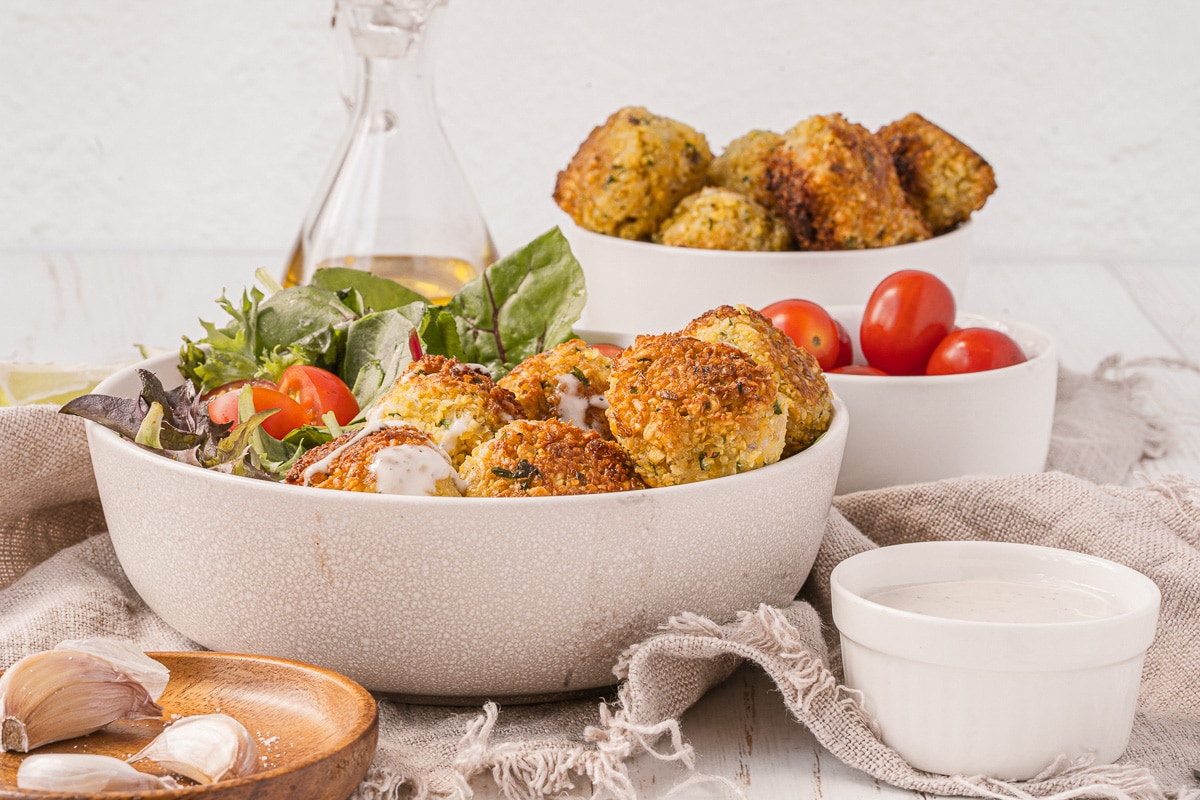 side view falafel bowl with ingredients in other bowls