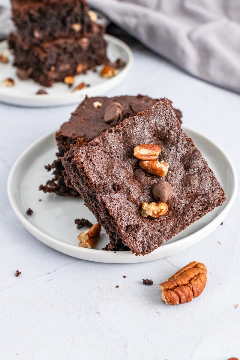 two almond flour brownies stacked on a plate