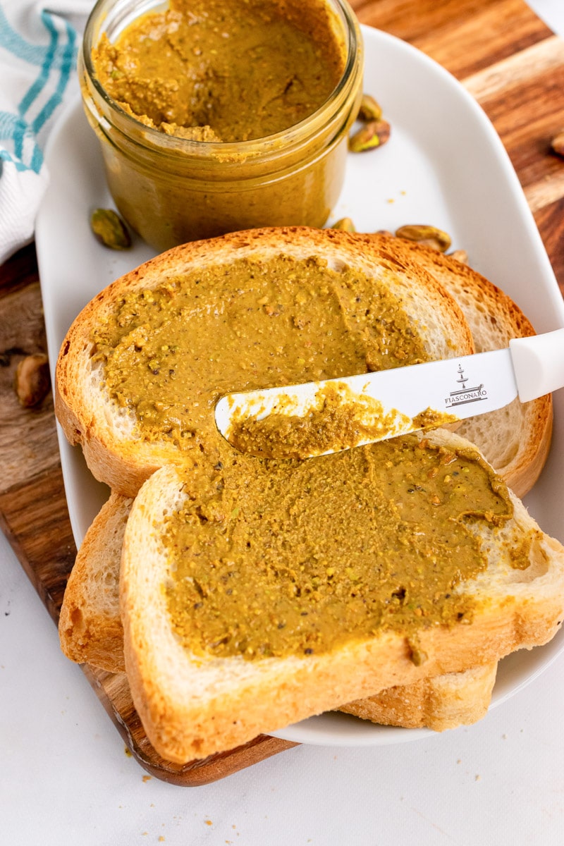 spreading pistachio butter on two slices of bread
