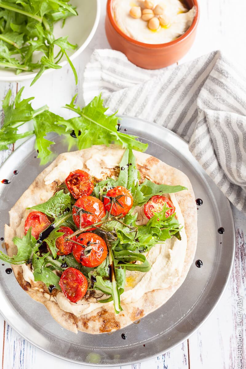 Hummus and Tomato Vegan Flatbread Pizza - A quick, easy and healthy light meal. Flatbreads are lightly toasted until crisp and topped with smooth creamy hummus, sweet cherry tomatoes, dandelion greens and tart balsamic for a satisfying meat-free lunch. | click for the recipe