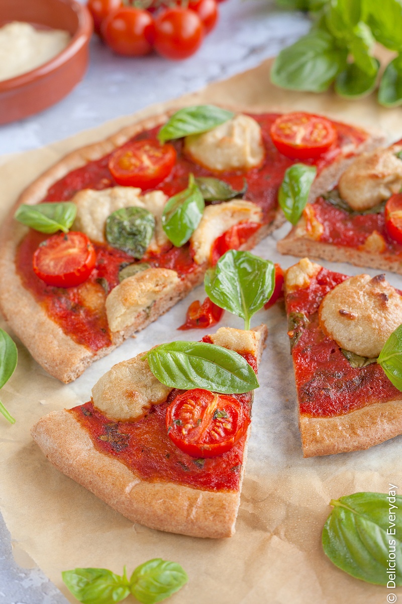 With this Vegan Pizza Recipe you can enjoy all the flavours of the Italian classic, the Margherita pizza. Topped with tomatoes and basil and a creamy cashew ricotta this cheeseless pizza is sure to be a hit! | Click for the recipe